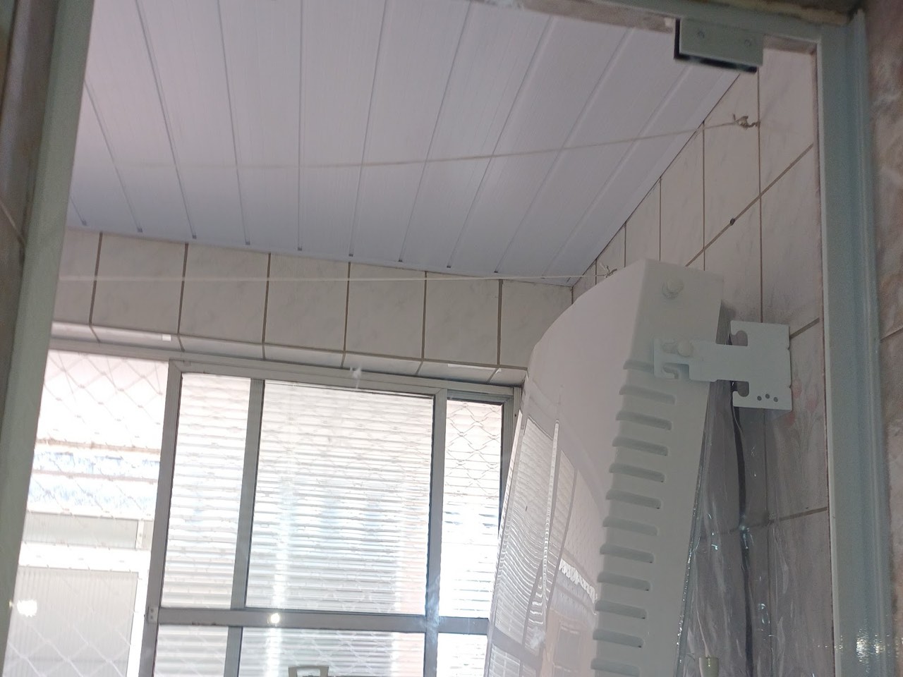 Janela de vidro instalada em área de serviço com forro de PVC