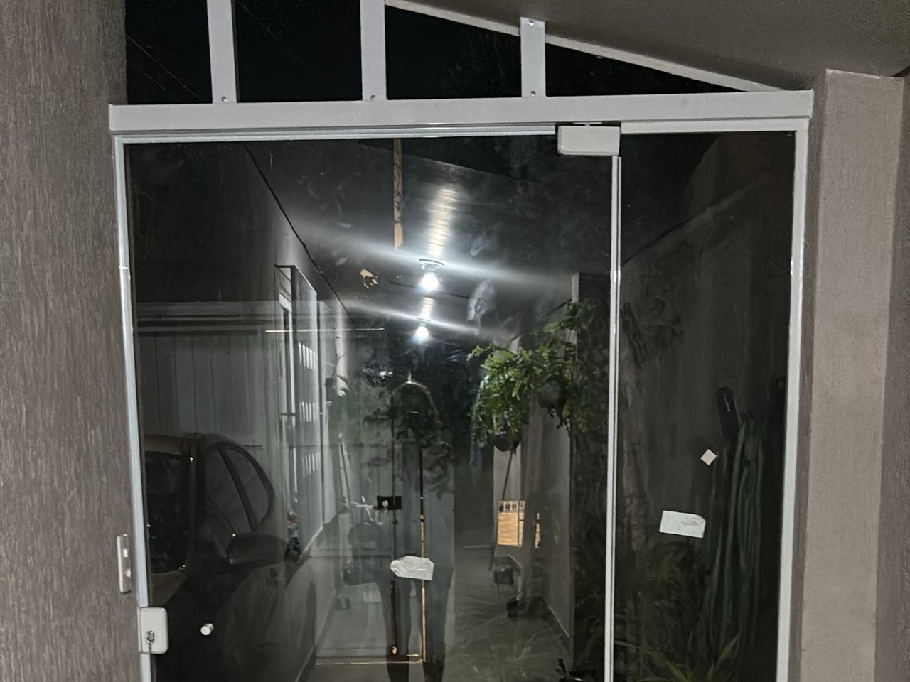 Porta de vidro de correr instalada em entrada residencial, foto noturna